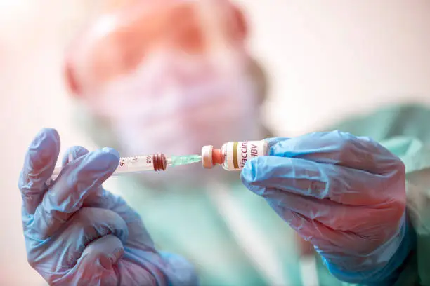 Photo of Doctor with protective face mask and gloves is preparing vaccine for HBV - Hepatitis