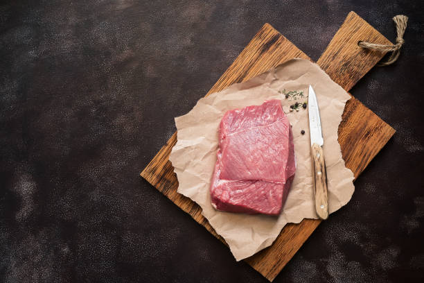 istock Raw fresh beef meat tenderloin on a wooden cutting board, dark rustic background. Top view, flat lay, copy space. 1225197464