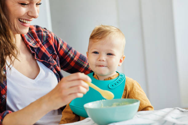 mother feeding baby food child eating family care childhood cute spoon Mther feeding baby boy a thome baby food stock pictures, royalty-free photos & images