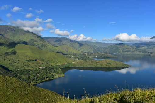 Calm water of Toba lake. Green mountains with the blue sky