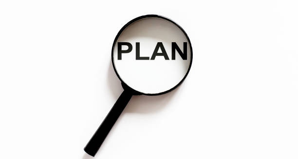 istock Opened old blank book with magnifying glass with text Plan 1225201086