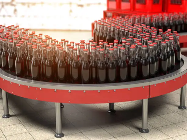 Photo of Production of soda bverages or cola. A row of bottles on conveyor belt in factory.