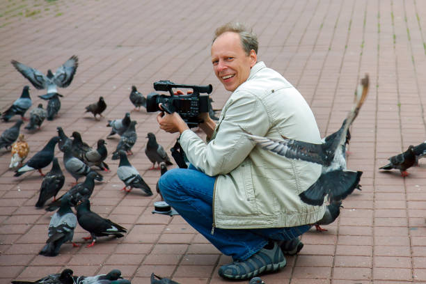 istock A man with a video camera attracted a flock of pigeons. 1225209362