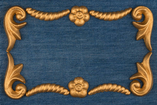 Frame made of gold-painted plaster molding lying on denim. Copy space. Top view. With space for your text