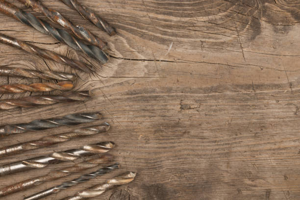 istock Old metal drills lie on a wooden surface. View from above. 1225214034