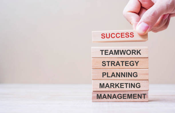 istock Businessman hand placing or pulling wooden block on the tower with text; Success, Teamwork, Strategy, Planning, Marketing and Management. Business concepts 1225215661