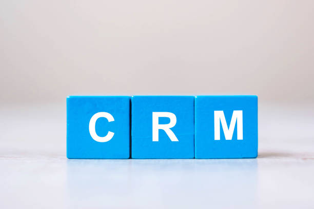 CRM text (Customer Relationship Management) cube blocks on table background. Financial, marketing and business concepts