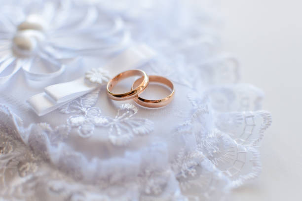 istock pair of gold wedding traditional rings on a white lace cushion 1225216708