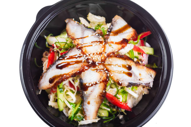 istock in a black deep plate, salad with sliced eel with teriyaki sauce, on an isolated white background 1225219450