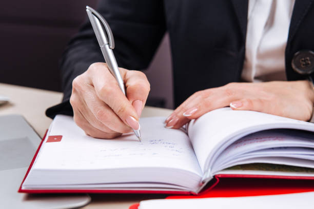istock Office female hand writing in a red daily planner 1225220919