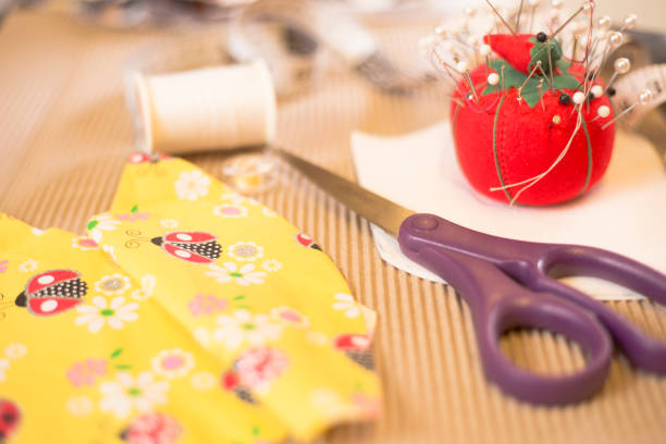 Cotton fabric, red scissors, measure tape and spool close up shot. Hobby and crafts concept