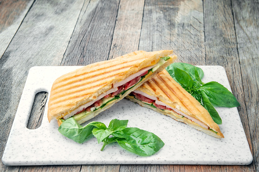 Healthy Grilled Basil mozzarella Caprese Panini Sandwich white Board on wooden table. Classic Italian fast food. Copy space