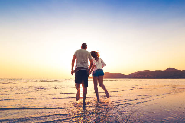 istock couple running and hand hold on the beach between sunset. 1225222392