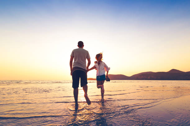 istock couple running and hand hold on the beach between sunset. 1225222393