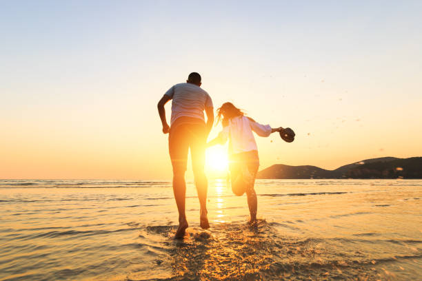 istock couple running and hand hold on the beach between sunset. 1225222396