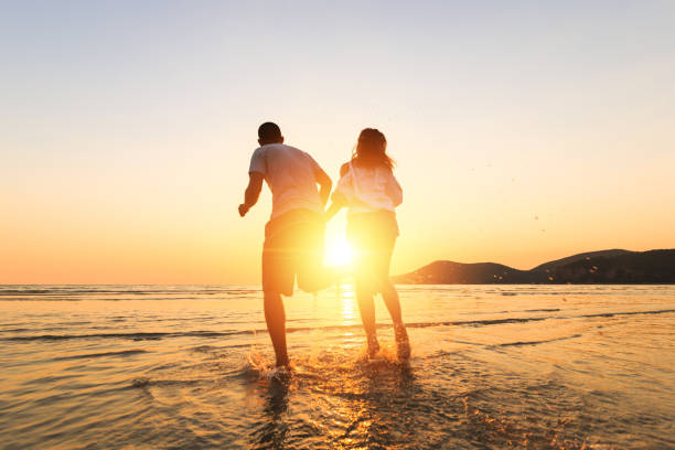 istock couple running and hand hold on the beach between sunset. 1225222400