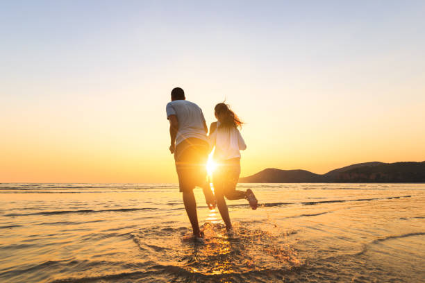istock couple running and hand hold on the beach between sunset. 1225222402