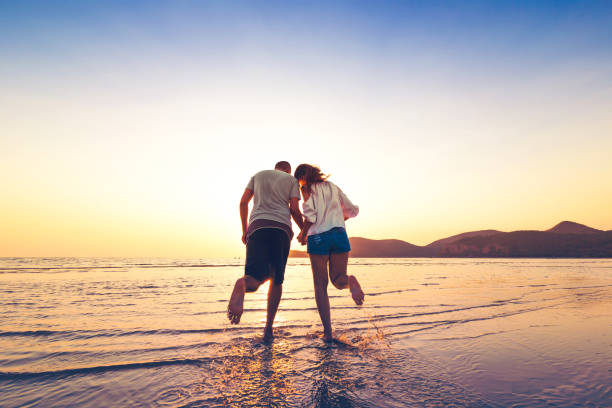 istock couple running and hand hold on the beach between sunset. 1225222404