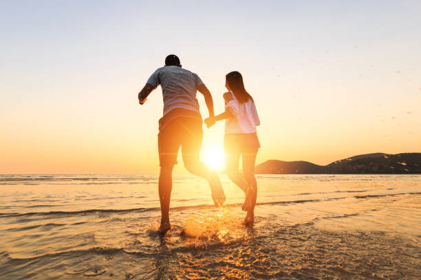 istock couple running and hand hold on the beach between sunset. 1225222405