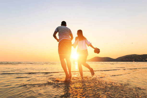 istock couple running and hand hold on the beach between sunset. 1225222411