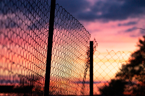 A photo of a beautiful sky, against the background of a fence, a rabitsa net. 
Rural landscape, outside the city in nature.