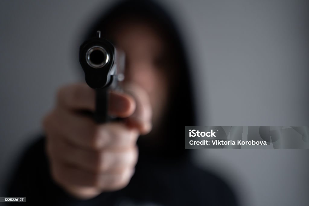 Criminal aiming gun camera, threatening burglar at victim Criminal aiming gun camera, threatening burglar at victim. Murder Stock Photo