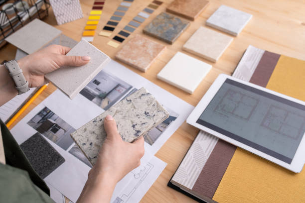 hands of young female designer holding two samples of marble tile over table - home improvement house home interior residential structure imagens e fotografias de stock