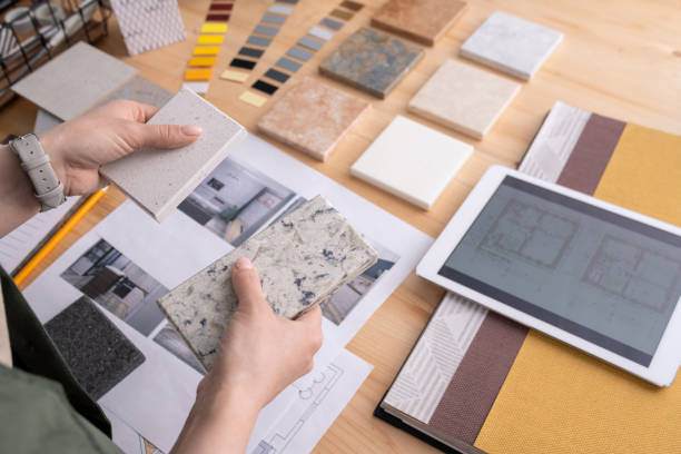 руки молодой женщины-дизайнера, держащей два образца мраморной плитки над столом - таблица цветов стоковые фото и изображения