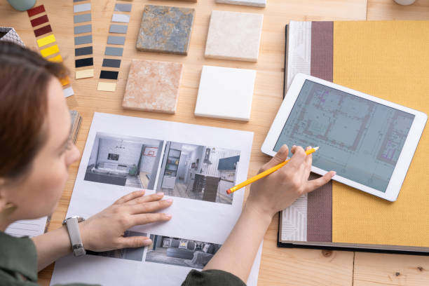 istock Creative female designer of interior looking through apartment plan in tablet 1225234134
