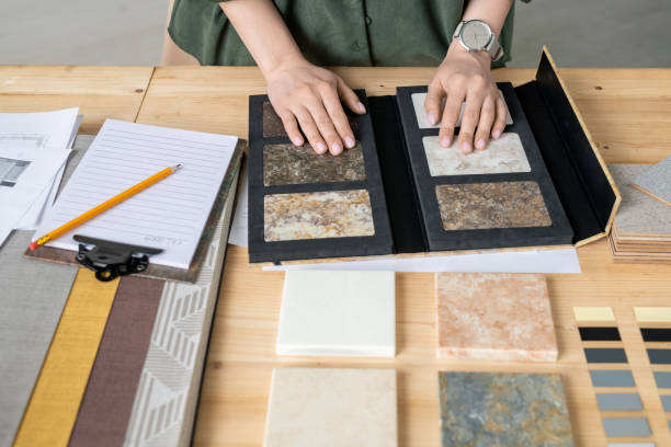 istock Hands of designer on samples of marble tile surrounded by wallpaper patterns 1225234148