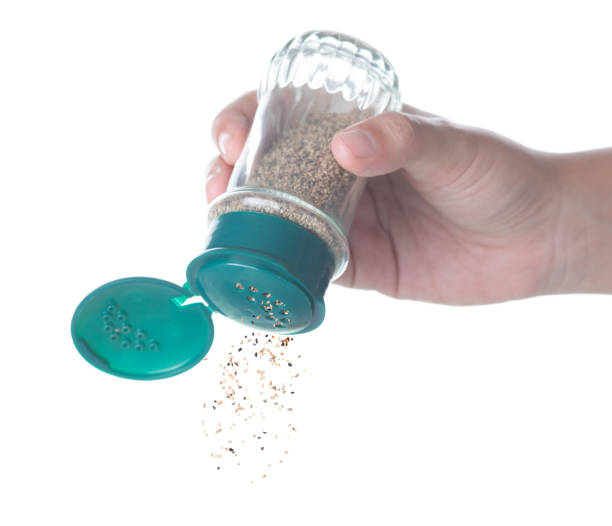 Hand holding bottle of black Pepper shaker on white background.