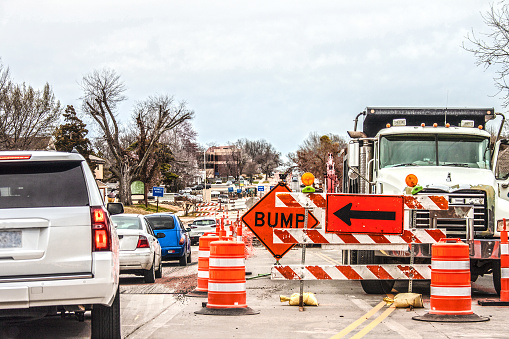 Trucks and road equipment on road with one lane blocked to horizon in urban area an cars navigation the construction