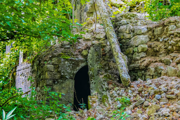 istock Collapsed rock and concrete bridge with arched opening underneath partly covered and tumbled rocks and debrie and overgrown vegetation 1225239373