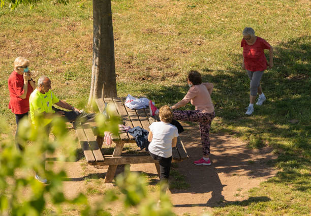 groupe de personnes âgées masquées et démasquées faisant de la gymnastique sur une pelouse à rome pendant l’auto-isolement - unmasked photos et images de collection