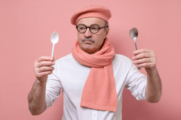 istock Senior funny caucasian man making choose between plastic and metal spoon 1225240180