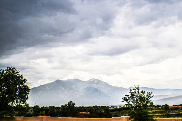 berge von taos new mexico aus gesehen, die wie glas aussehen, mit licht, das morgens mit nebel durch sie scheint - new mexico landscape sky ethereal stock-fotos und bilder