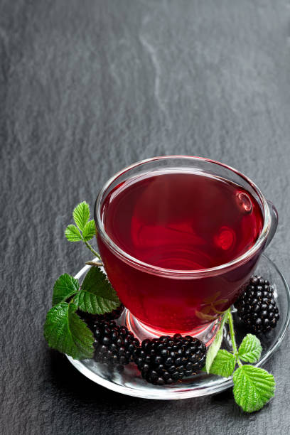 istock Fresh blackberry tea in glass cup on black stone background 1225251571