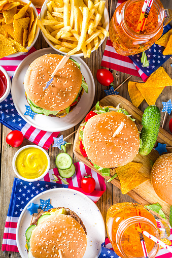 Celebrating Independence Day, July 4. Traditional American Memorial Day Patriotic Picnic with burgers,  french fries and snacks, Summer USA picnic and bbq concept, Old wooden background