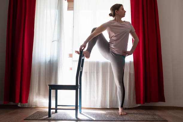 istock Young woman doing yoga doing lone raised leg balance using chair. 1225257900