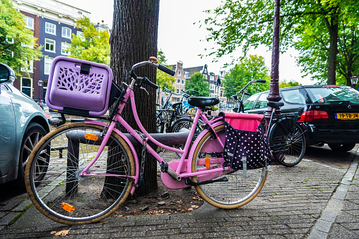 Amsterdam, Netherlands - September 8, 2018: Old pink vintage bicycle parked on a street in Amsterdam, Netherlands