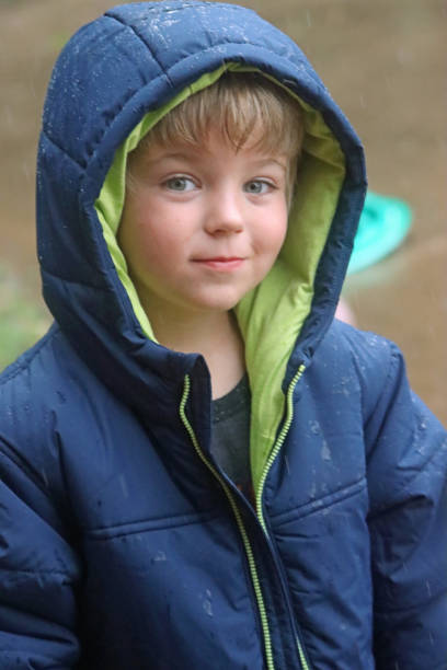 istock Young blond caucasian boy in jacket with hood up looking at camera 1225260936