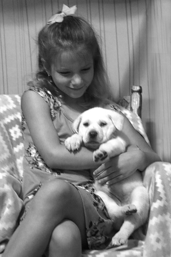 Young caucasian female girl holding young puppy, black and white