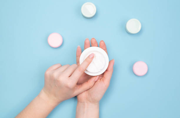 istock Female hand apply cosmetic cream on blue background, top view 1225262305