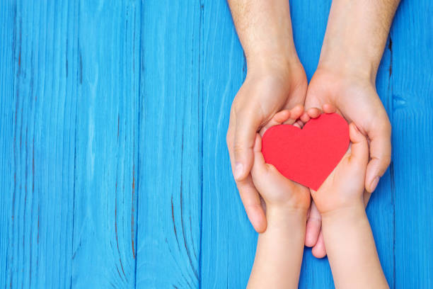istock Child and dad hands holding red heart. 1225265807
