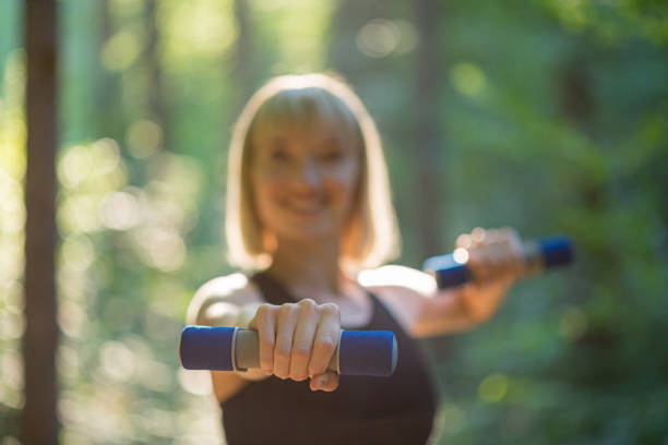 istock Young woman exercising with small hand weights outside in a forest 1225265994