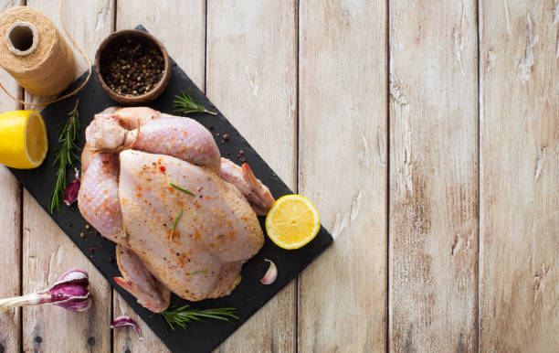 Raw whole chicken with lemon, rosemary and garlic