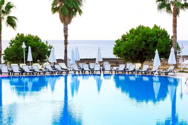 Tropical empty pool view with white beach chairs. Social distancing, cancellation of vacation, crisis of tourism business concept during lockdown, quarantine because of coronavirus, covid-19.