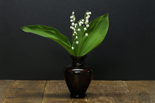 A bouquet of lilies of the valley in a small vase is on the table