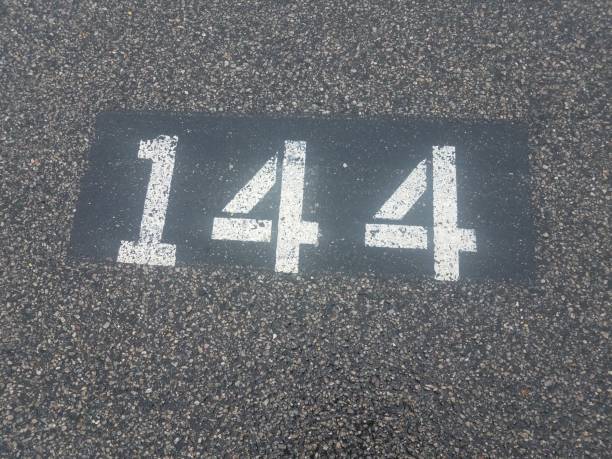 number 144 painted on black asphalt or pavement