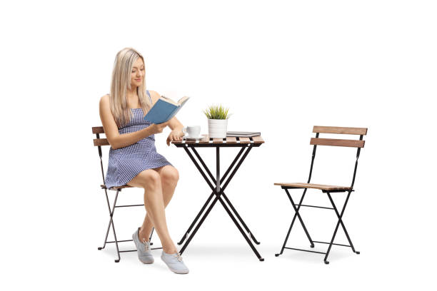 istock Young woman sitting at a table and reading a book 1225272272